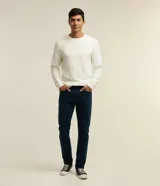 Pantalón de jean corte slim, color azul oscuro, con cierre de botón y cremallera, trabillas para cinturón y bolsillos laterales y traseros.