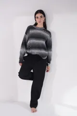 Suéter de tejido grueso con diseño de rayas horizontales en degradé de gris a negro. Presenta apliques de piedras brillantes distribuidas de forma irregular en el frente y mangas. Tiene cuello redondo y un calce holgado.
