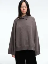 Sweater de lana superfina color gris, con corte holgado, mangas largas y cuello alto con medio cierre lateral.