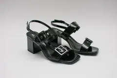 Sandalias negras acharoladas con doble hebilla y taco cuadrado.