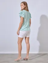 Blusa color verde agua con cuello redondo fruncido y lazo. Tiene mangas cortas con volados.