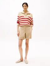 Sweater de punto color crema con rayas horizontales rojas, cuello alto con cremallera metálica y logo de Tommy Hilfiger bordado en el pecho.