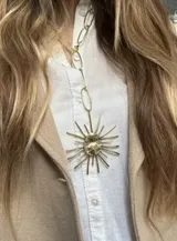 Collar largo de bronce con cadena de eslabones ovalados y dije central en forma de sol con centro ovalado texturizado y rayos de diferentes longitudes.