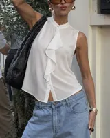 Camisa blanca sin mangas, confeccionada en tela ligera, con cuello mao, botón superior visible y detalle de volados en la parte delantera.