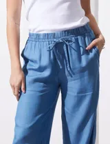 Pantalón celeste de lyocell, corte ancho, con pretina elastizada con lazo de ajuste, bolsillos verticales y ruedo desflecado.