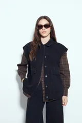 Chaleco de jean con corte oversized, diseño sin mangas, cuello camisero, cierre frontal con botones metálicos y bolsillos frontales tipo cargo.
