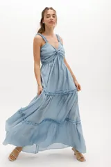 Vestido largo celeste de gasa de algodón con textura liviana. Tiene escote en V con nudo central, breteles con voladitos y frunces en la falda.