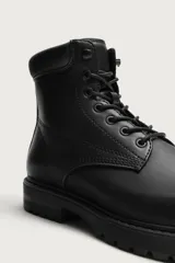 Bota tipo derby con cordones, confeccionada en material liso con horma redonda y suela track con volumen.