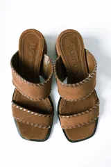 Sandalias tipo mule de taco medio, confeccionadas en cuero gamuzado color terracota. Presentan dos tiras anchas con detalles de costuras pespunteadas en los bordes y taco cuadrado estable.