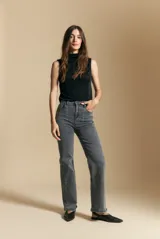 Jean de corte recto y tiro medio, color gris oscuro con efecto lavado. Presenta apliques de tachas metálicas pequeñas en la zona de los bolsillos delanteros.