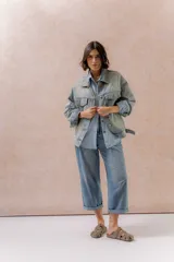Campera de denim oversized en lavado celeste, con hombros caídos, cierre frontal con botones metálicos, bolsillos delanteros con tapa y aplicaciones de strass con diseño orgánico en delantero, mangas y espalda.