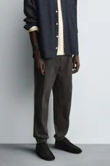 Pantalón tipo jogger de corte slim fit, confeccionado en tejido de algodón con elasticidad. Presenta cintura elástica ajustable con cordón, bolsillos frontales, bolsillos traseros de vivo y bajos con puños elásticos.