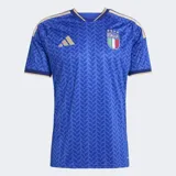 Camiseta de fútbol Adidas de manga corta para hombre, color azul con patrón geométrico en tono más oscuro. Presenta cuello en V con ribete dorado y detalles en los hombros con las tres franjas de Adidas en dorado. Incluye el escudo de la FIGC (Italia) en el pecho izquierdo y el logo de Adidas en el derecho.