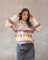 Sweater de tejido de punto con diseño nórdico y geométrico multicolor sobre base color crema. Presenta cuello redondo, mangas largas amplias con puños ajustados y un calce relajado.