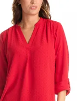 Blusa de corte holgado con escote en V y cuello mao. Presenta mangas largas con sistema de ajuste mediante presilla y botón, permitiendo regular su largo. Confeccionada en tejido con textura sutil.