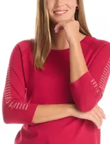 Buzo de tejido fino en color blanco, con cuello redondo y mangas tres cuartos tipo raglán. Presenta un detalle decorativo de tachas metálicas a lo largo de las mangas.