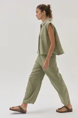 Blusa verde militar sin mangas, confeccionada en lino, con cuello camisero, cierre frontal con botones y corte holgado.