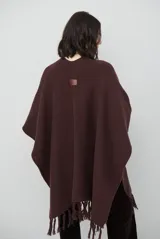 Ruana de tejido de punto en color negro, con diseño de cuello alto y terminaciones con flecos en los bordes.