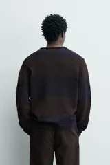 Jersey de punto de algodón con ajuste relajado, cuello redondo y manga larga. Presenta un diseño de rayas horizontales anchas en tonos azul marino y marrón oscuro.