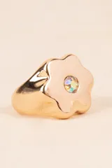Anillo dorado con forma de flor y detalle de cristal iridiscente en el centro.