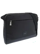 Bolso tipo mensajero o bandolera de color negro, con cuerpo principal de tela y base de material sintético liso. Presenta un bolsillo frontal con cierre metálico y un parche pequeño con el logo de Calvin Klein. Incluye una correa ajustable de tela negra.