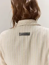 Blazer de lino color negro con pespuntes en contraste de hilo tostado, cuello solapa amplia, cierre frontal con un botón de madera y bolsillos aplicados.