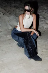 Jeans de corte wide leg en denim negro lavado, con inserción lateral de encaje negro adornado con flecos y lentejuelas.