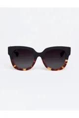 Lentes de sol Tiwi modelo Kerr, con armazón de diseño bicolor que combina la parte superior en negro mate y la parte inferior con estampado carey. Cuentan con cristales oscuros degradados y protección UV.