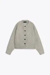 Chaqueta de punto de cuello redondo y manga larga, con cierre frontal de botones y acabados en rib.