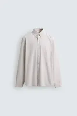 Camisa de corte regular fit confeccionada en tejido de algodón con estampado de cuadros pequeños. Presenta cuello abotonado, manga larga con puños abotonados, bolsillo de plastrón en el pecho y cierre frontal con botones.