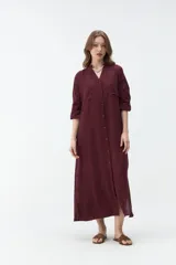 Vestido largo color bordó, tipo camisero, con cuello mao, escote en V y cierre frontal con botones. Mangas largas con vuelta y diseño holgado.