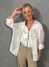 Camisa de seda color blanco crudo, con estampado en relieve bordado de hojas, cuello camisero, mangas largas y cierre frontal con botones.