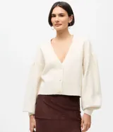 Cardigan de punto color crema con escote en V, cierre frontal de botones y mangas largas abullonadas con puños acanalados. Presenta un diseño corto y ajuste cómodo.
