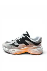 Championes deportivos en combinación de gris y beige, con diseño chunky de suela gruesa texturizada con detalles en tono anaranjado, cordones blancos y detalles laterales en relieve.