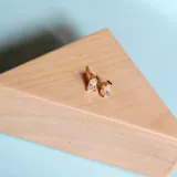 Par de aros dorados con pasante, con forma rectangular y cristales cúbicos incrustados.