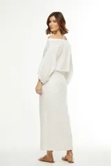 Falda midi color amarillo pálido, de corte recto con abertura frontal y cinturón con hebilla circular.