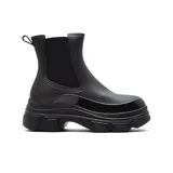 Bota de lluvia tipo Chelsea, color negro, con caña media y elástico lateral. Presenta una suela track gruesa y dentada, con puntera y detalles en charol brillante.