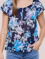 Blusa de gasa semitransparente color azul marino con estampado floral en tonos celestes y lilas, cuello redondo elastizado con lazo central y mangas cortas con doble volado.