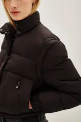 Campera puffer color tostado, con cierre frontal y botones a presión, cuello alto y puños tejidos acanalados.