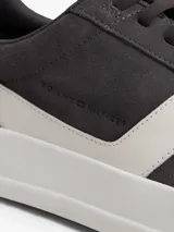 Zapatillas de tenis Tommy Hilfiger de corte bajo, confeccionadas en ante color gris con paneles en contraste de color blanco. Presentan cierre con cordones, suela de goma blanca y logo de la marca grabado en el lateral y el talón.