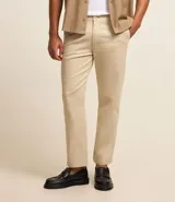 Pantalón de vestir color marrón, de corte slim y largo cropped. Confeccionado en tejido de algodón liso, con bolsillos laterales y traseros. Cierre frontal con botón y cremallera.