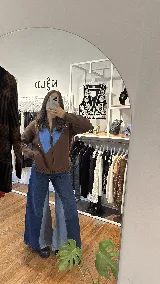 Campera tejida de hilo color marrón chocolate con cierre frontal y diseño de gran corazón azul en el centro. Cuenta con detalles bordados en los costados del pecho.