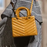 Cartera bandolera color camel de símil cuero soft con diseño acolchado en forma de chevron. Tiene acceso con cierre y broches imantados, correa regulable, herrajes dorados, tres compartimentos y bolsillos internos.