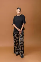 Remera negra de corte holgado con cuello redondo y mangas cortas. Presenta un diseño asimétrico en el ruedo con detalle de encaje negro.