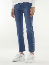 Pantalón jean azul de corte recto, con terminación desflecada y botones dorados en el ruedo.