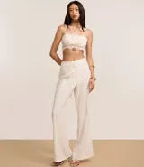 Pantalón flare de tejido plano color blanco, con trabillas en la cintura, cierre tradicional, frisos delanteros y bolsillos falsos atrás.