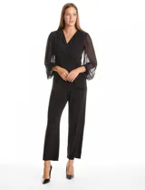 Enterito de seda fría color negro, con escote en V cruzado y cintura elástica con lazo lateral. Presenta mangas largas de gasa transparente con puños elásticos fruncidos y pantalón de corte recto al tobillo.