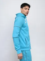 Campera deportiva Umbro de piqué, color celeste, con capucha, cierre frontal completo y detalles de piping en las mangas.
