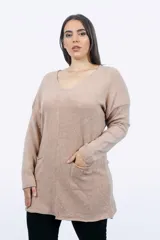 Buzo largo color beige, de corte holgado y mangas largas, con cuello en V y dos bolsillos delanteros.