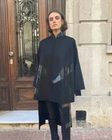 Capa negra de paño de lana con cuello mao y cierre frontal con ganchos ocultos. Estampado serigráfico negro brillante en cuerpo y cuello.